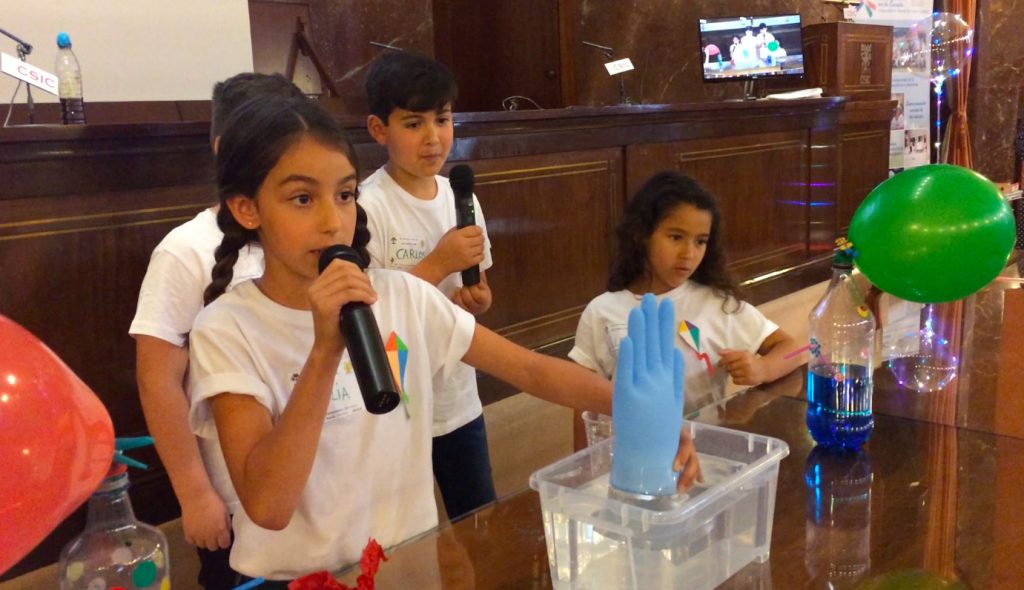 El CSIC en la Escuela: semillas plantadas hoy para la Ciencia de mañana Una alumna del colegio Colegio Clara Campoamor, de Bormujos (Sevilla), explica por qué el guante se llena de aire en una cubeta de agua durante el VIII Encuentro Científico de El CSIC en la Escuela.