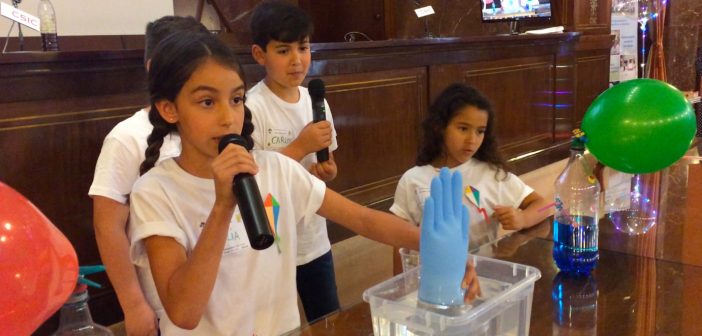 Una alumna del colegio Colegio Clara Campoamor, de Bormujos (Sevilla), explica por qué el guante se llena de aire en una cubeta de agua durante el VIII Encuentro Científico de El CSIC en la Escuela.